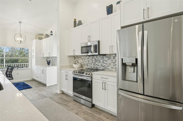 kitchen with white cabinets, light wood-type flooring, tasteful backsplash, decorative light fixtures, and stainless steel appliances