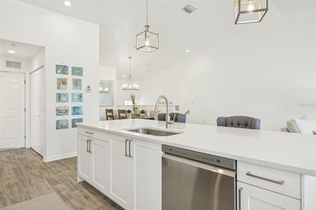 kitchen featuring white cabinetry, sink, stainless steel dishwasher, light hardwood / wood-style floors, and decorative light fixtures