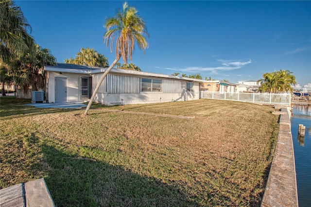 exterior space featuring cooling unit, a water view, and a front lawn