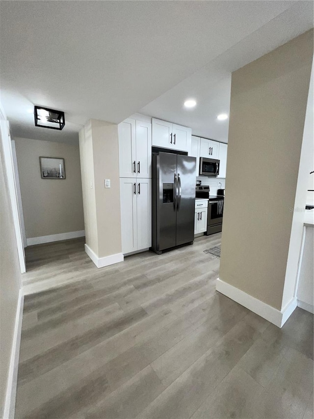 kitchen featuring white cabinetry, light hardwood / wood-style flooring, stainless steel appliances, and a textured ceiling