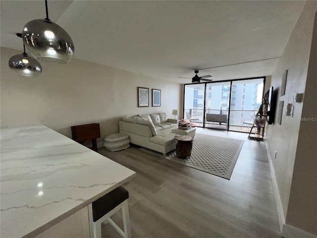 living room with hardwood / wood-style floors, ceiling fan, and a wall of windows