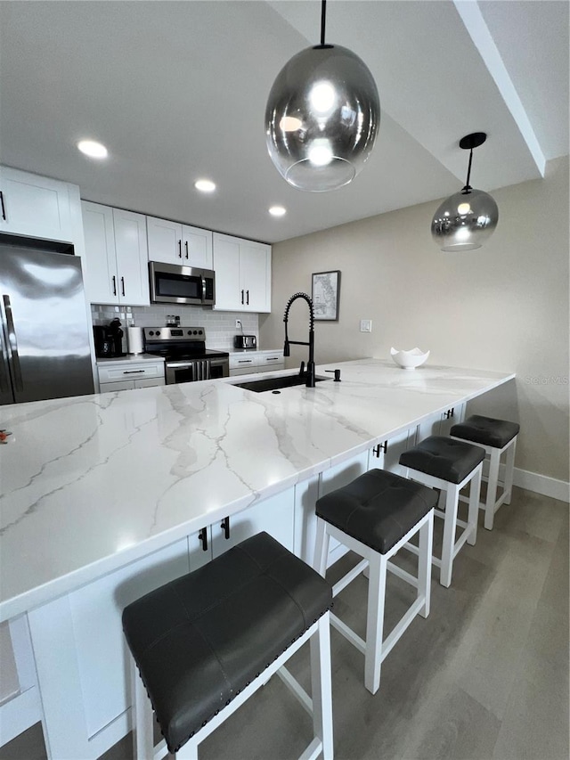 kitchen featuring pendant lighting, sink, kitchen peninsula, and stainless steel appliances