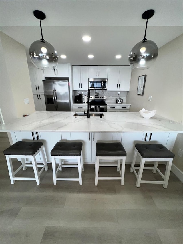 kitchen featuring light stone countertops, appliances with stainless steel finishes, decorative light fixtures, and sink