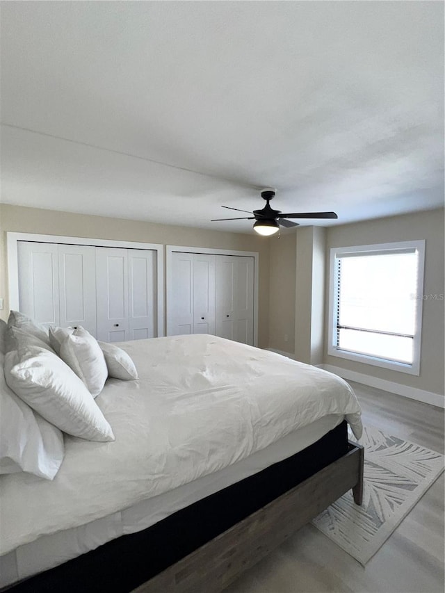 bedroom with multiple closets, ceiling fan, and hardwood / wood-style floors