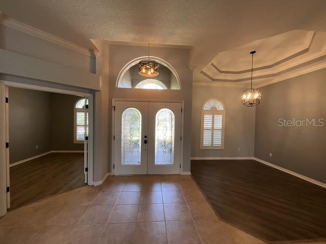 tiled entrance foyer with ornamental molding, an inviting chandelier, and plenty of natural light