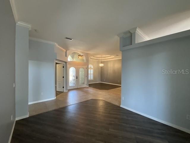foyer with visible vents, baseboards, ornamental molding, wood finished floors, and a notable chandelier