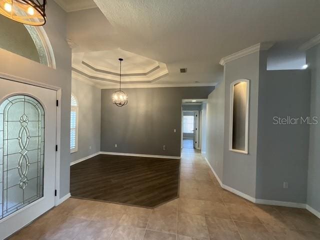 entryway featuring baseboards, an inviting chandelier, tile patterned flooring, and crown molding