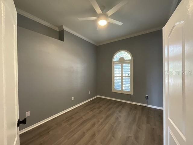 spare room with ceiling fan, ornamental molding, dark wood-style floors, and baseboards