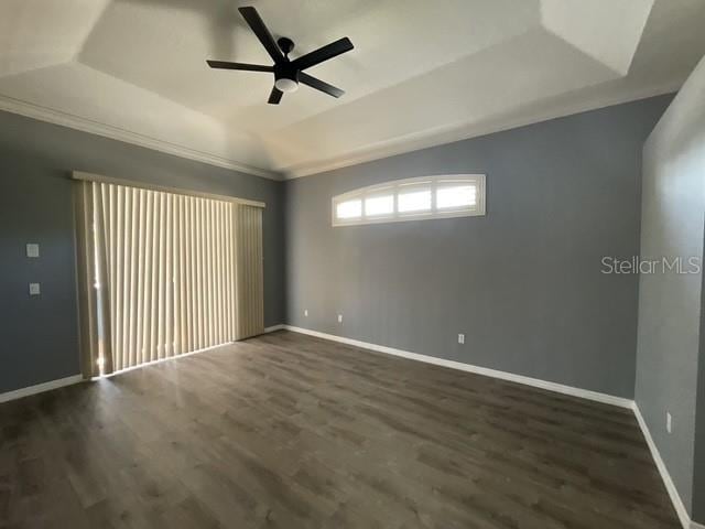 empty room with baseboards, a ceiling fan, dark wood-style flooring, and a tray ceiling