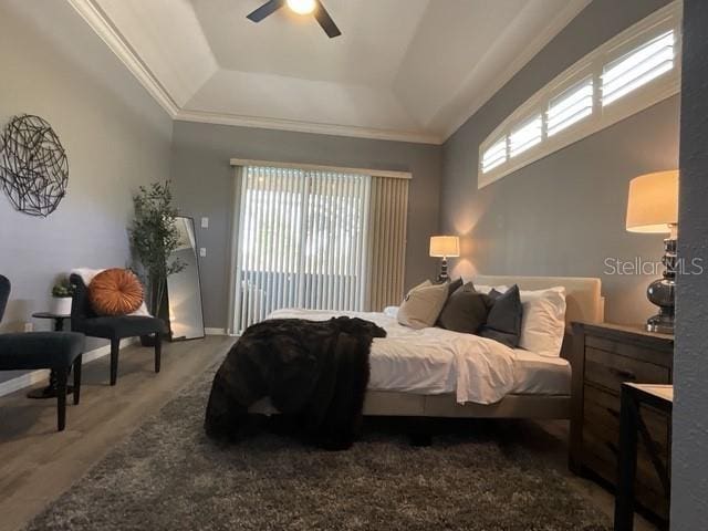 bedroom with crown molding, a tray ceiling, a ceiling fan, and multiple windows
