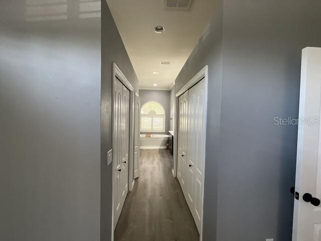 corridor with dark wood finished floors, visible vents, and baseboards