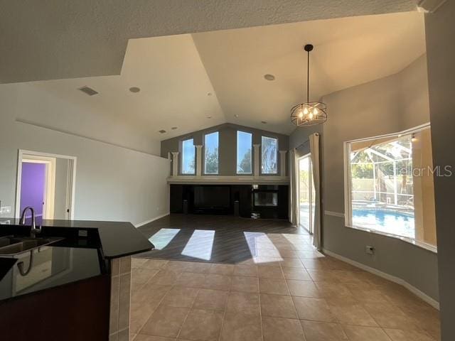 interior space with lofted ceiling, visible vents, baseboards, a glass covered fireplace, and light tile patterned flooring
