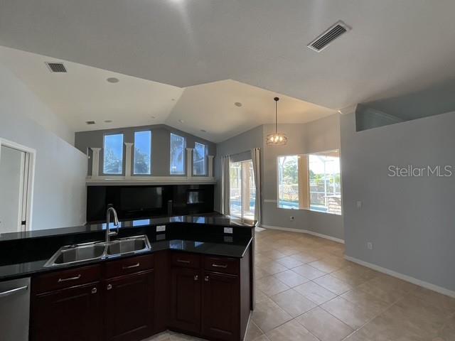 kitchen featuring lofted ceiling, a sink, dark countertops, visible vents, and open floor plan