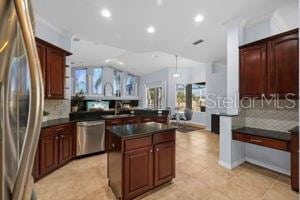 kitchen with dark countertops, a peninsula, appliances with stainless steel finishes, and decorative backsplash