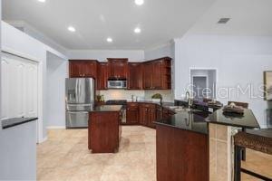 kitchen featuring dark countertops, stainless steel appliances, a kitchen island, recessed lighting, and a peninsula