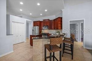 kitchen with stainless steel microwave, a breakfast bar area, a peninsula, baseboards, and refrigerator