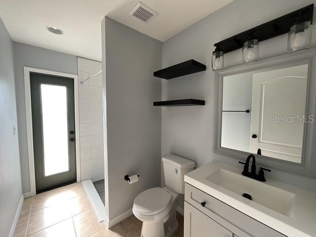 full bath with visible vents, baseboards, toilet, tile patterned floors, and tiled shower