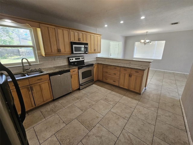 kitchen with kitchen peninsula, stainless steel appliances, sink, a notable chandelier, and hanging light fixtures