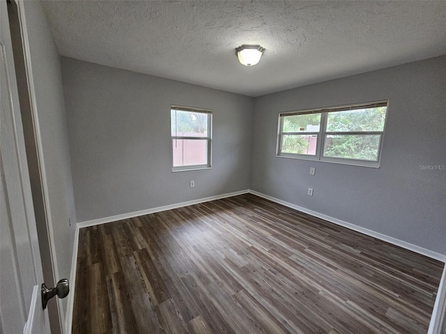 empty room with a textured ceiling and dark hardwood / wood-style floors