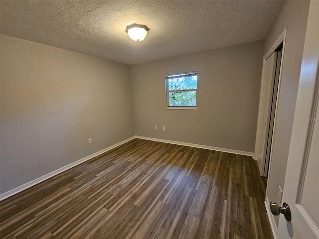 unfurnished bedroom featuring a textured ceiling, a closet, and dark wood-type flooring