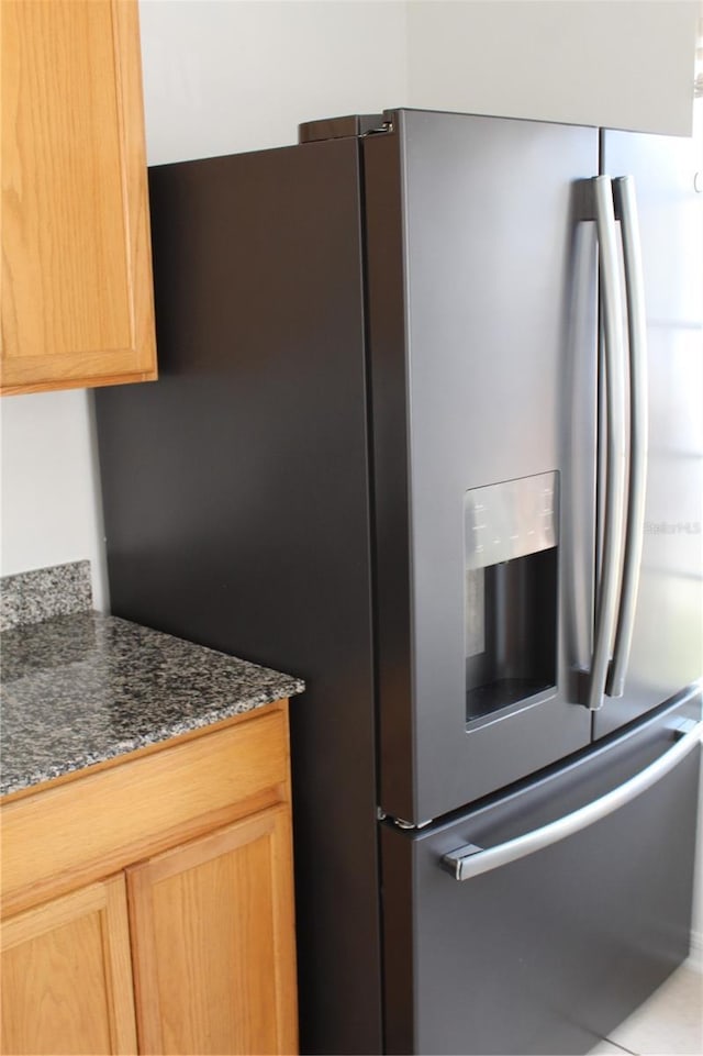 kitchen featuring stainless steel fridge with ice dispenser and dark stone counters