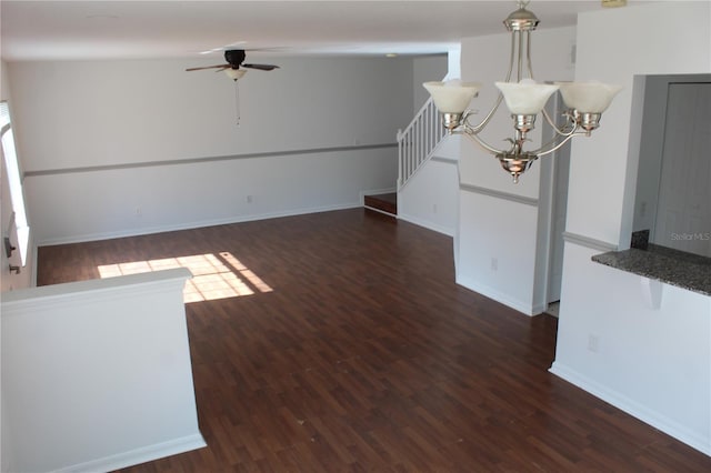 unfurnished living room featuring ceiling fan with notable chandelier and dark hardwood / wood-style floors