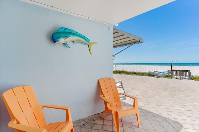 view of patio / terrace with a water view and a view of the beach