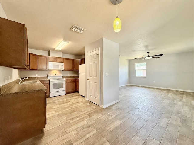 kitchen featuring visible vents, a sink, ceiling fan, white appliances, and light wood-style flooring