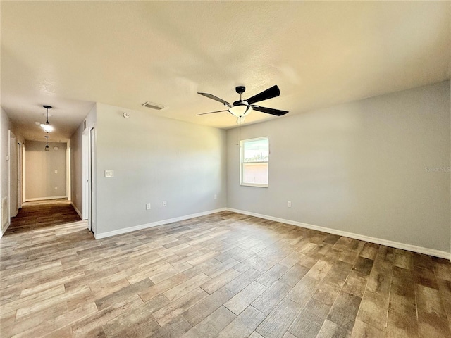 spare room featuring visible vents, baseboards, a ceiling fan, and wood finished floors