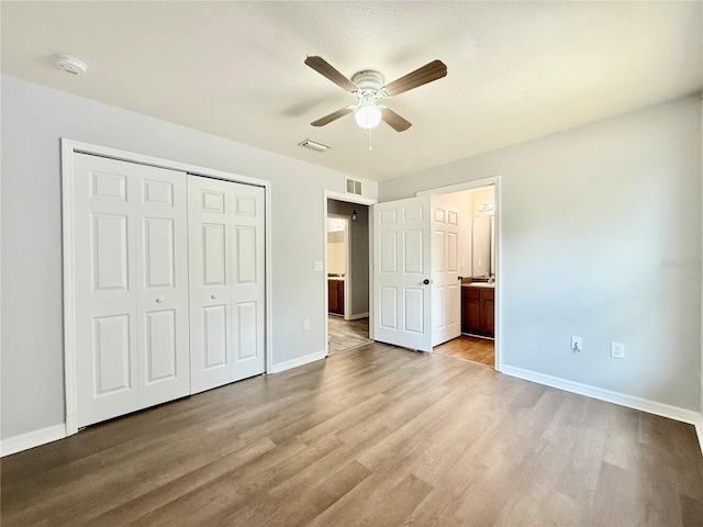 unfurnished bedroom with baseboards, wood finished floors, a closet, and visible vents