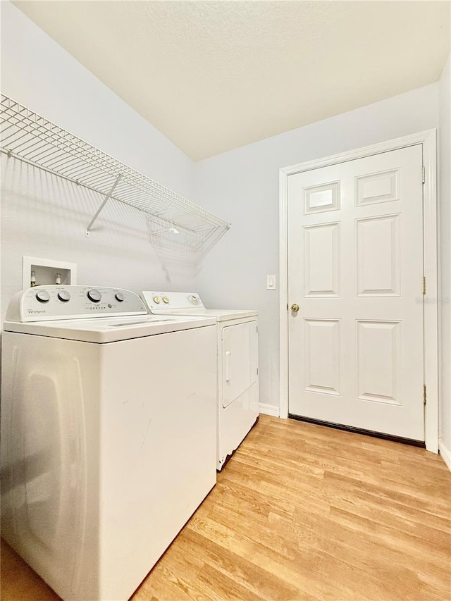 laundry area featuring washer and dryer, laundry area, light wood finished floors, and baseboards