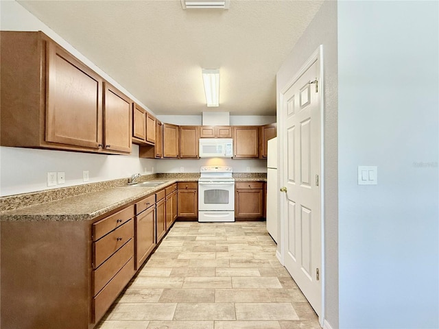 kitchen with light wood-type flooring, white appliances, brown cabinets, and a sink