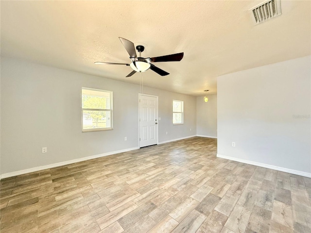 unfurnished room with ceiling fan, a textured ceiling, visible vents, wood finished floors, and baseboards