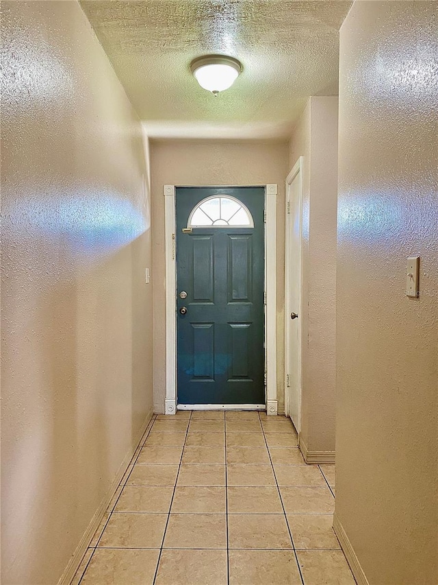 doorway to outside featuring light tile patterned floors and a textured ceiling