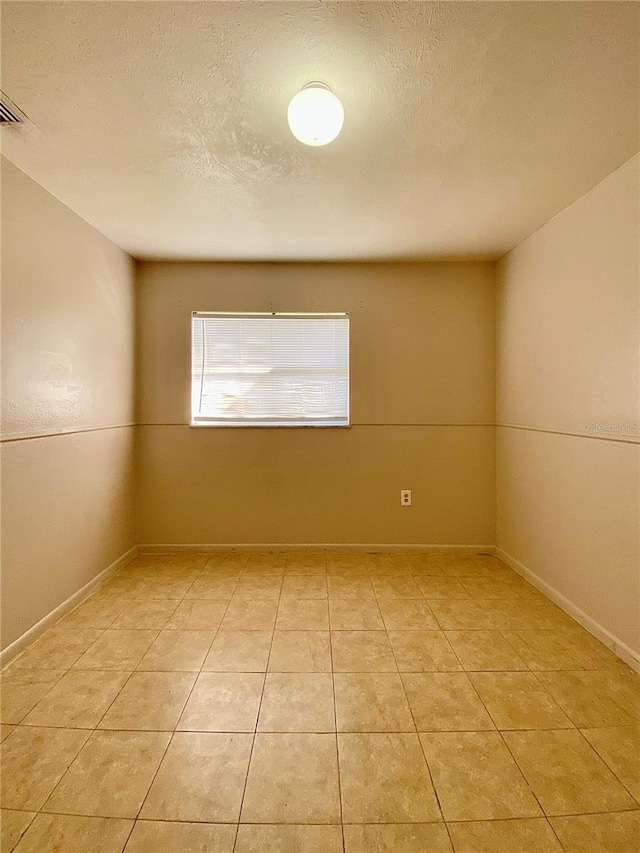 tiled empty room featuring a textured ceiling