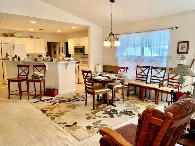 dining area with light colored carpet, vaulted ceiling, and an inviting chandelier