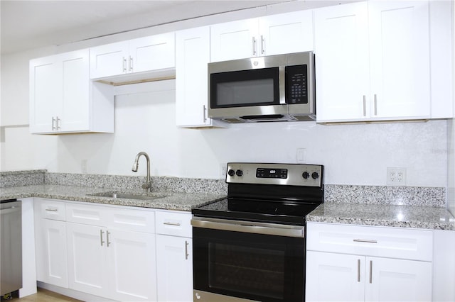 kitchen with white cabinetry, sink, light stone countertops, and appliances with stainless steel finishes