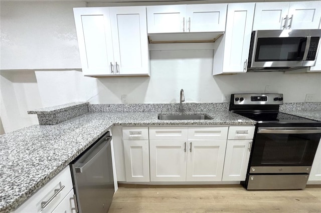 kitchen featuring white cabinetry, sink, appliances with stainless steel finishes, and light hardwood / wood-style flooring