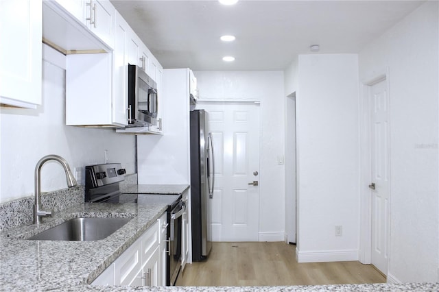 kitchen with light stone countertops, stainless steel appliances, sink, light hardwood / wood-style flooring, and white cabinetry