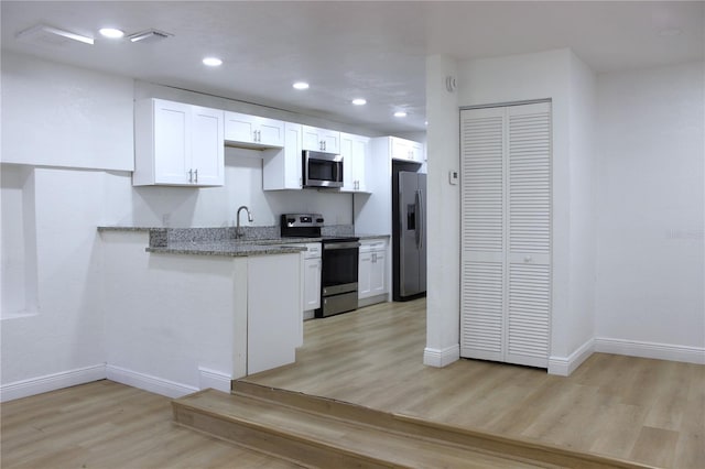 kitchen with white cabinets, stainless steel appliances, light hardwood / wood-style flooring, and light stone countertops