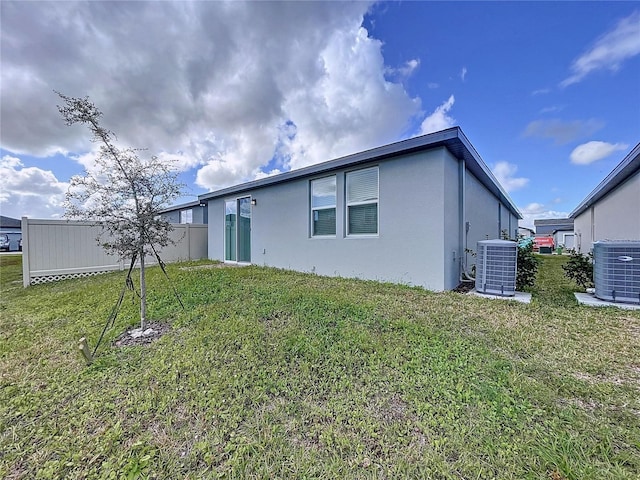 rear view of property with central air condition unit and a yard