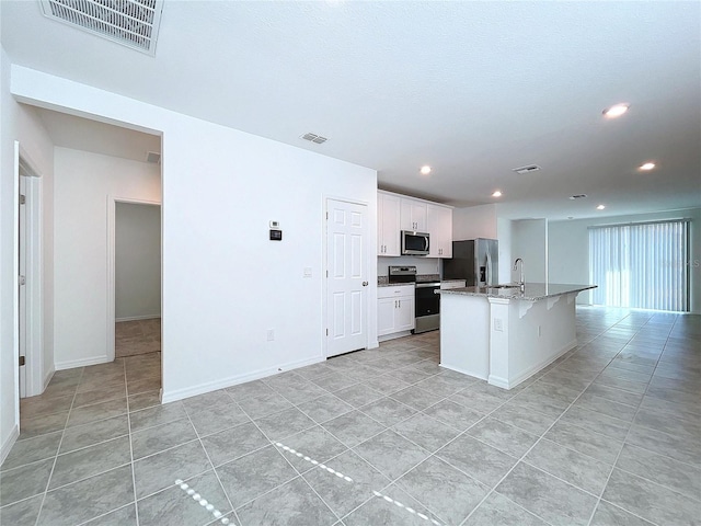 kitchen with sink, light tile patterned flooring, an island with sink, white cabinets, and appliances with stainless steel finishes