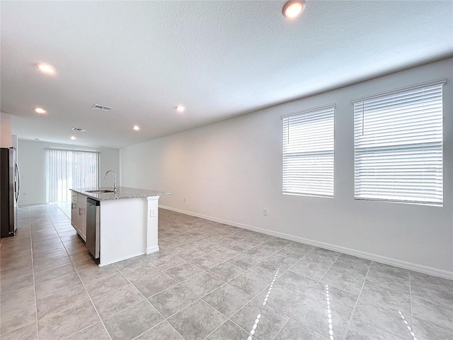 kitchen with appliances with stainless steel finishes, sink, plenty of natural light, and an island with sink