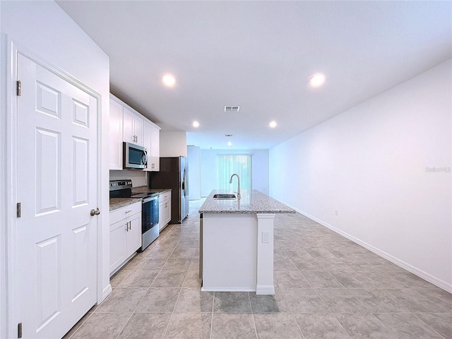 kitchen with white cabinets, light stone countertops, a kitchen island with sink, and appliances with stainless steel finishes