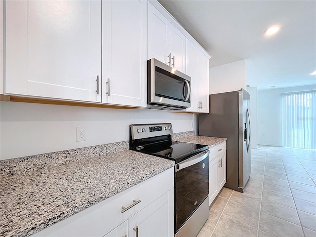 kitchen with white cabinetry, light tile patterned floors, light stone countertops, and appliances with stainless steel finishes