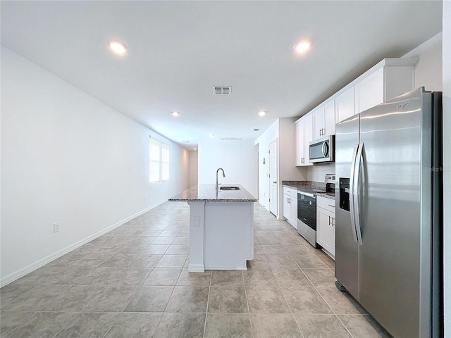 kitchen featuring light stone countertops, stainless steel appliances, a kitchen island with sink, sink, and white cabinets