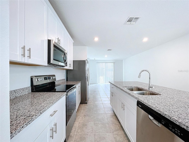 kitchen with light stone countertops, sink, light tile patterned floors, white cabinets, and appliances with stainless steel finishes