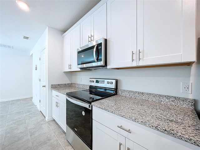 kitchen with light stone countertops, appliances with stainless steel finishes, light tile patterned floors, and white cabinetry