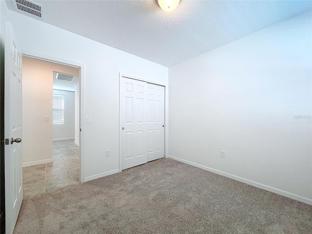 unfurnished bedroom featuring a closet, light colored carpet, and a textured ceiling