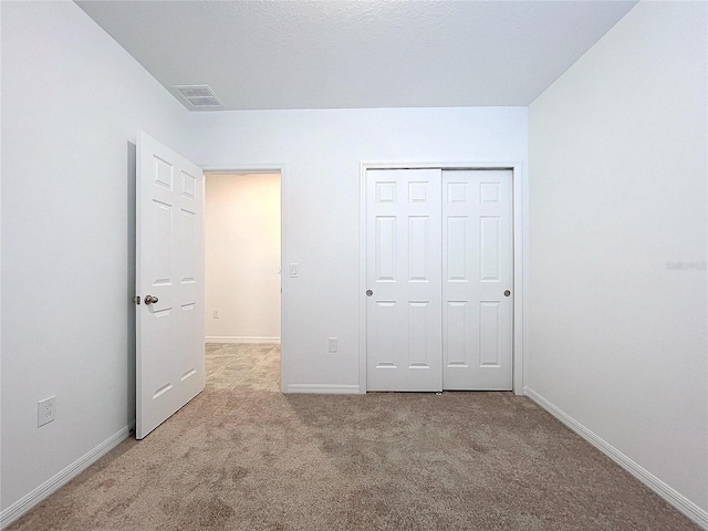 unfurnished bedroom featuring light carpet and a closet